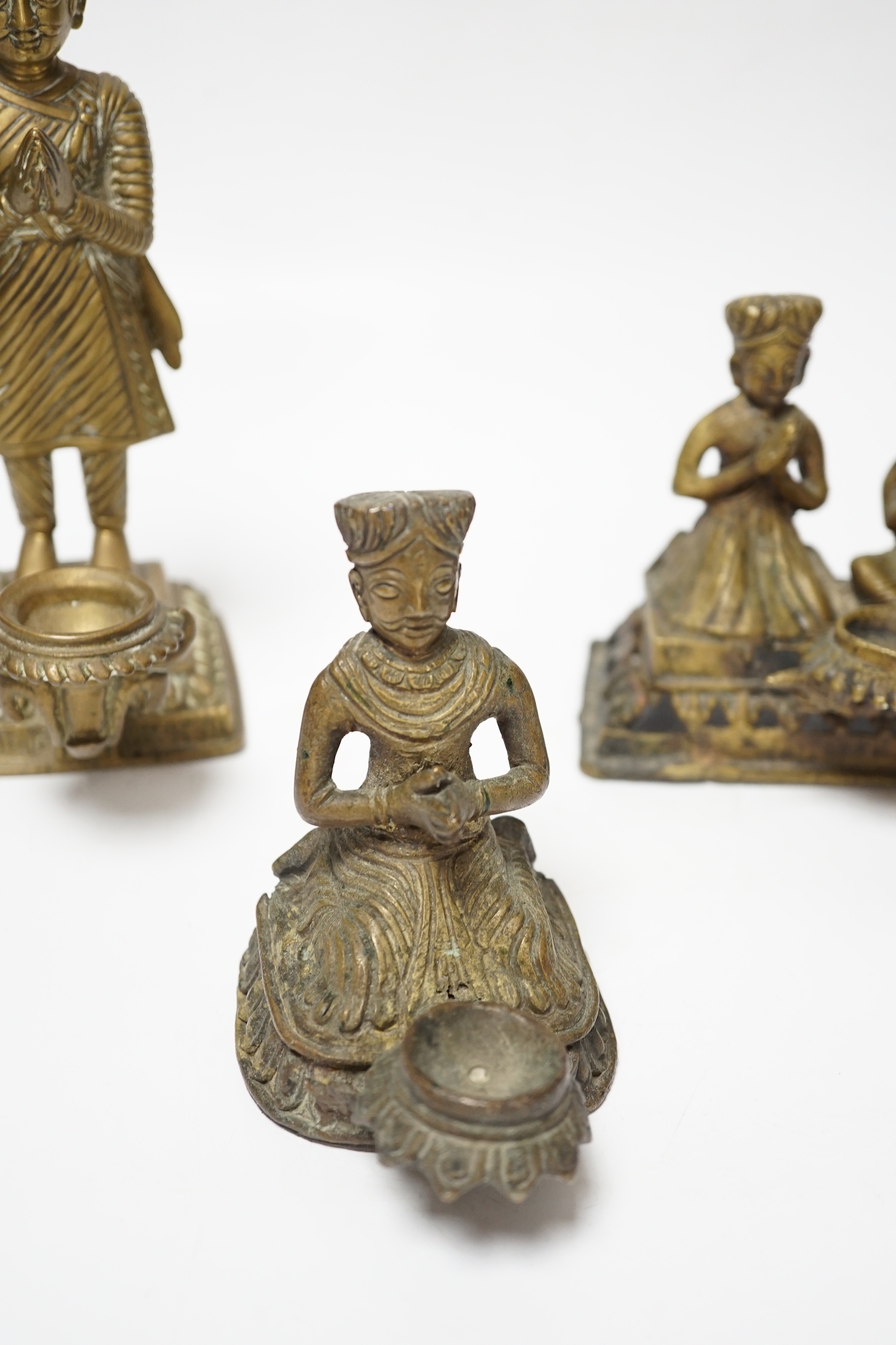 Three Nepalese figural brass oil lamps, 18th/19th century